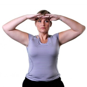 A woman in a sleeveless top with her hand on her head, appearing to be in a state of distress or discomfort.