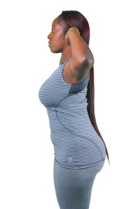 A woman with long hair, wearing a gray tank top, standing against a white background.