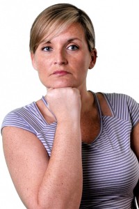 The image features a woman with short hair, wearing a striped top, posing with her hand on her chin.