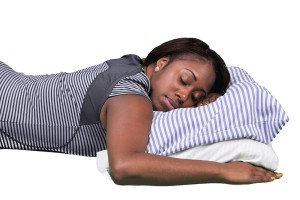 A woman lying on her side with a pillow, wearing a black and white striped dress.