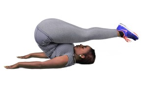 Woman in a gym performing a handstand on a balance board.