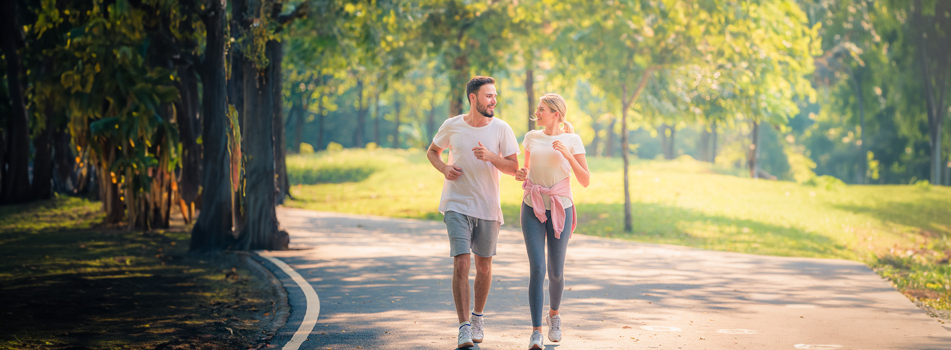 A man and a woman walking together on a sidewalk, with the man holding the woman s hand.