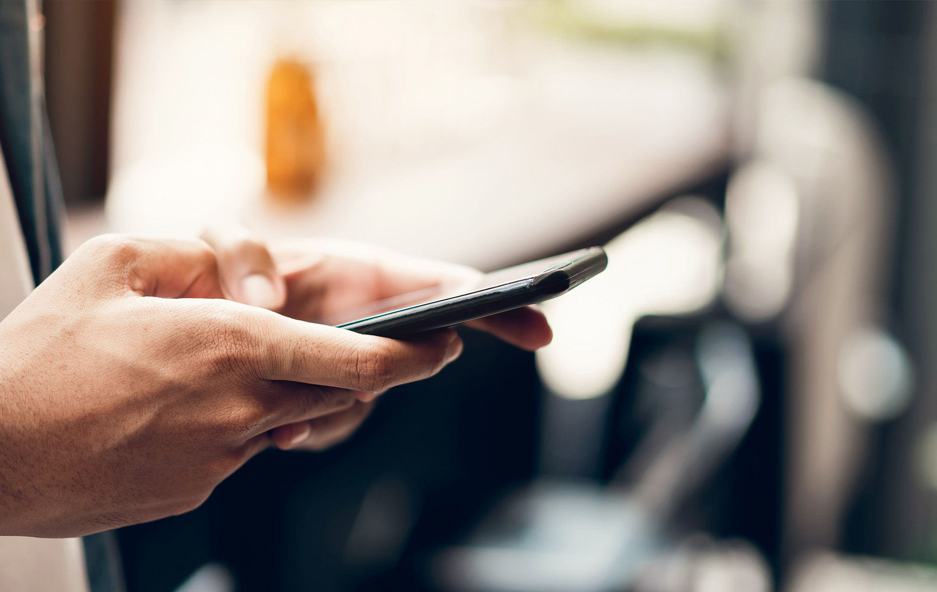 The image shows a person using a smartphone, with the device held in their hand and the screen visible.