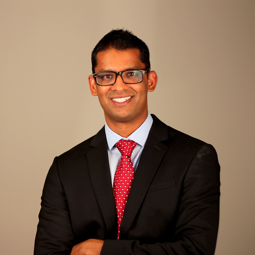 A man in a suit and tie, smiling at the camera.